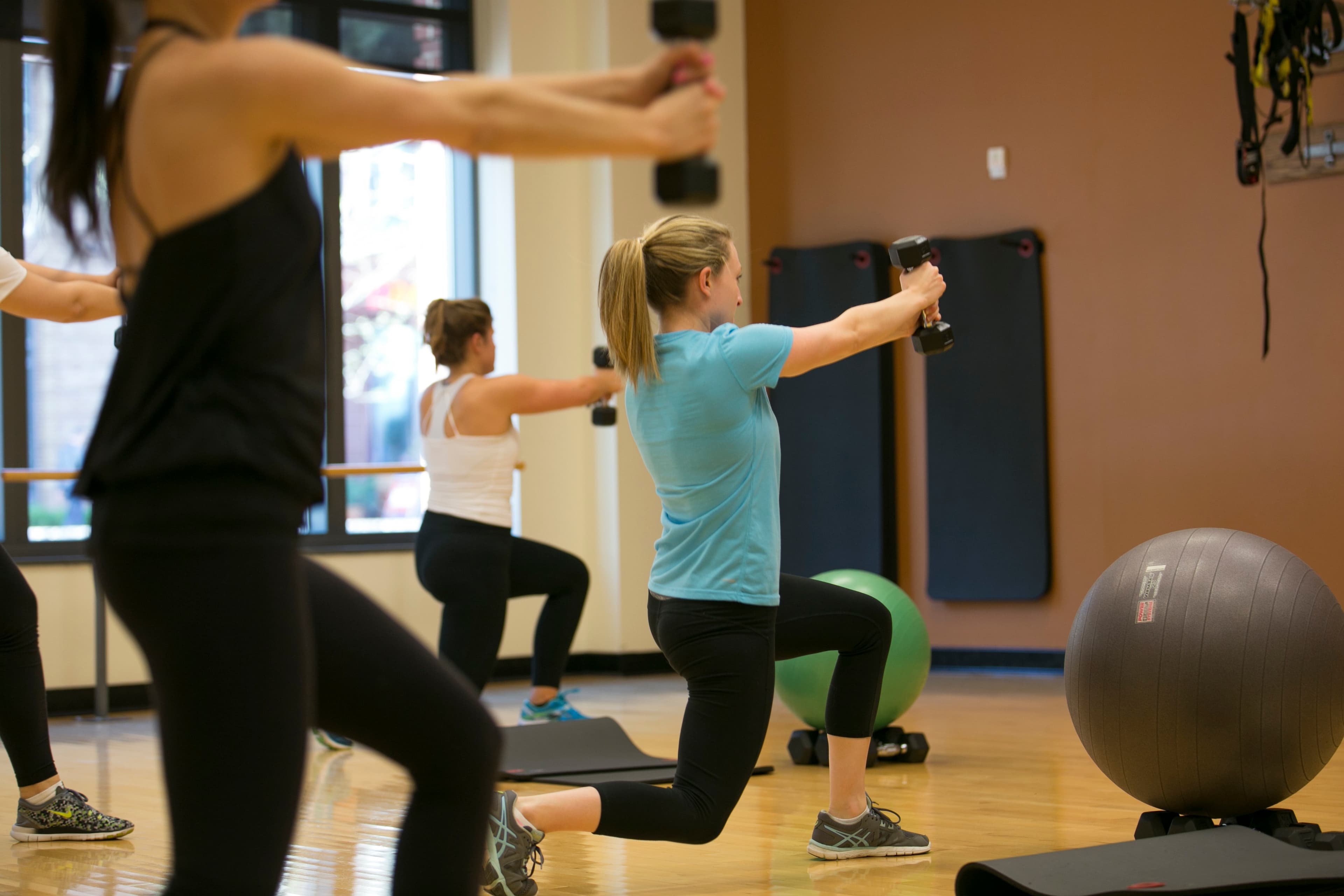 A group strength class lunging with dumbbells
