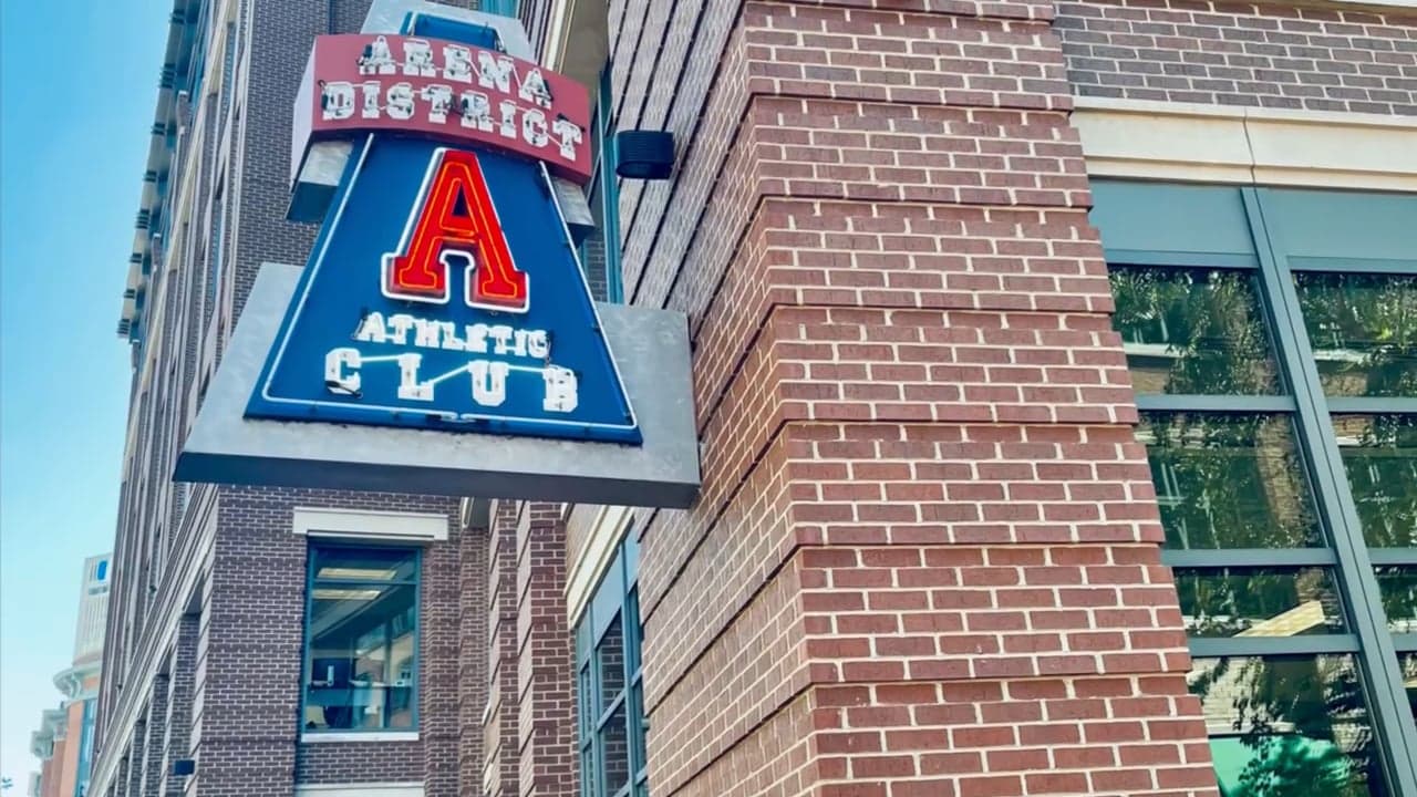 The vintage Arena District Athletic Club neon sign hanging from the brick building
